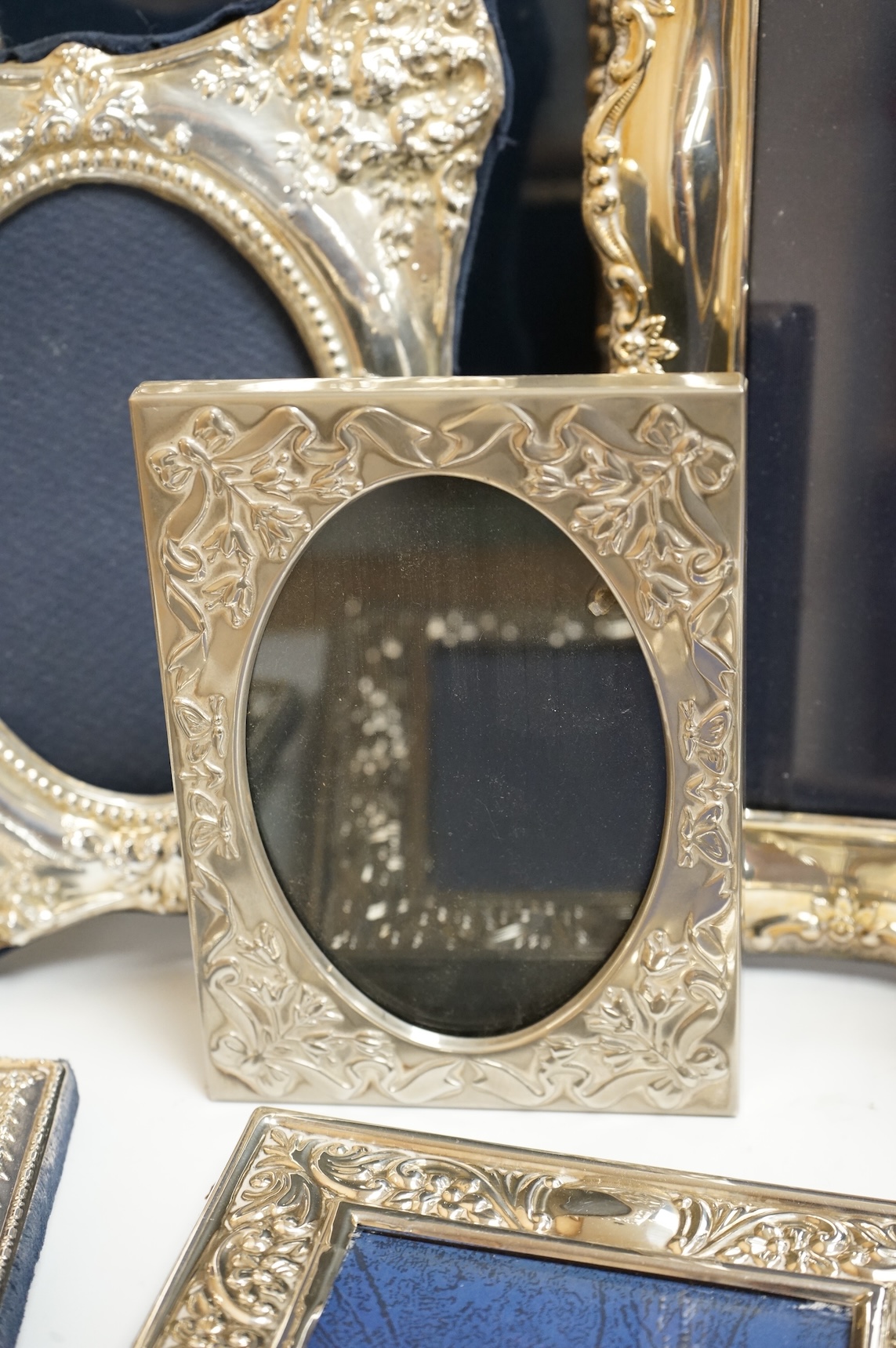 A George V silver mounted rectangular photograph frame, with ribbon bow crest, by Stokes & Ireland Ltd, Chester, 1912, 18.2cm including crest, together with ten other modern silver mounted photograph frames, largest 29.4